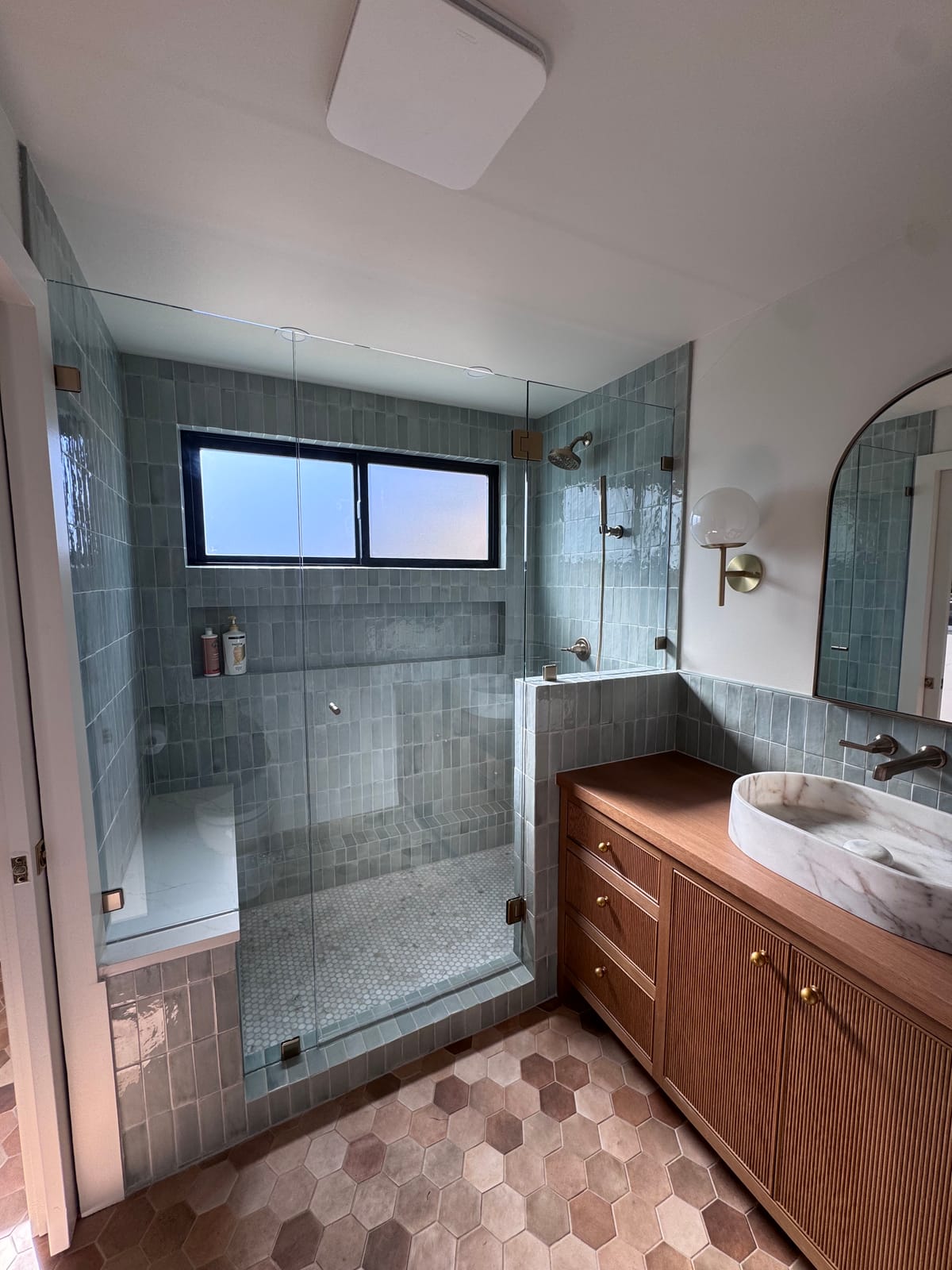 Bathroom remodel in Whitford near Tigard — glazed green tile walk-in shower, wood slat vanity, and hex tile floor by K&H Construction