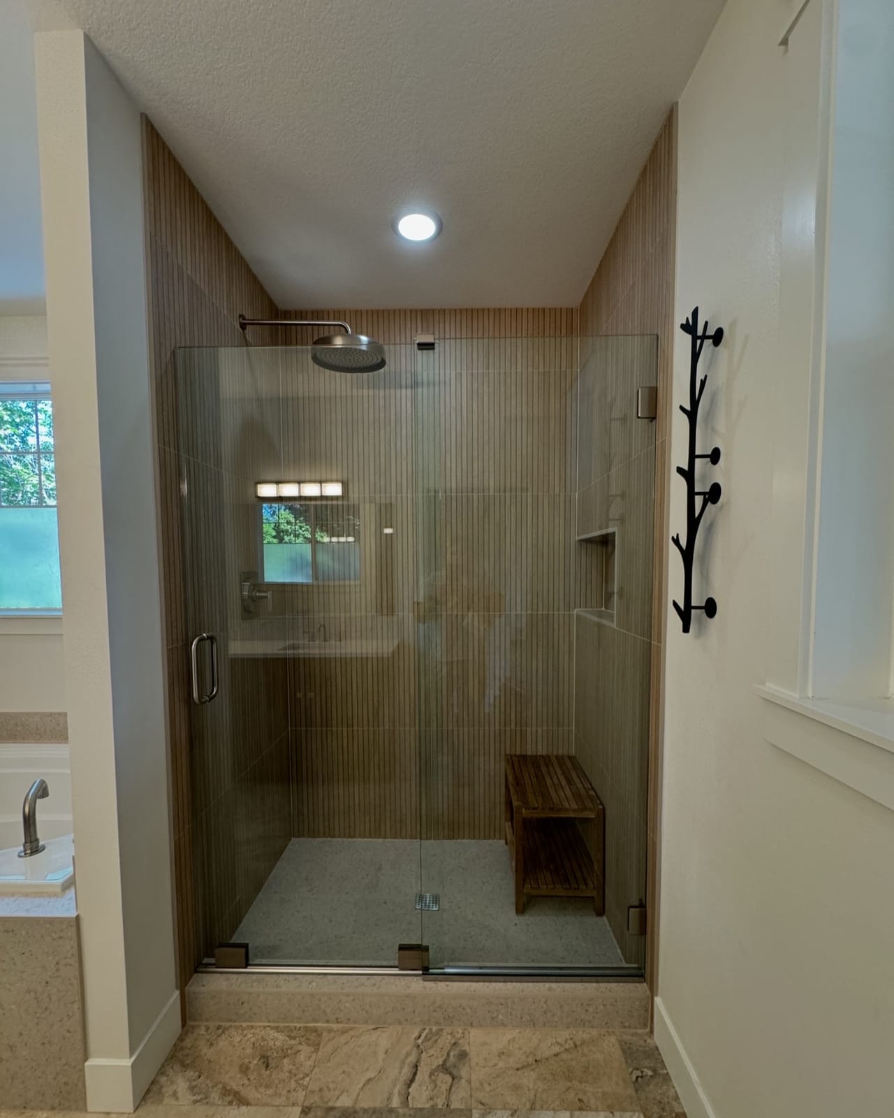 After: frameless glass walk-in shower with rain head, built-in bench, and wood-look tile in a West Slope master bathroom — K&H Construction