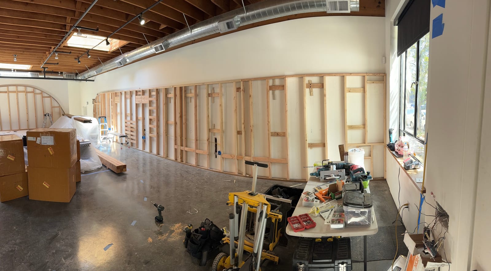 Commercial build-out in progress at a Portland studio space — new wall framing and custom arches under the original timber ceiling, by K&H Construction