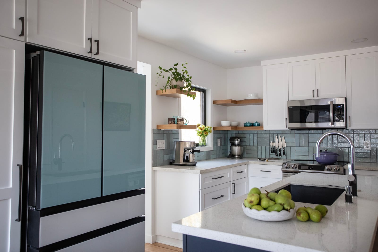 Two-tone kitchen from a whole-home renovation in Cully, NE Portland — white perimeter cabinets, dark island, glass-front refrigerator, subway tile, and quartz counters by K&H Construction