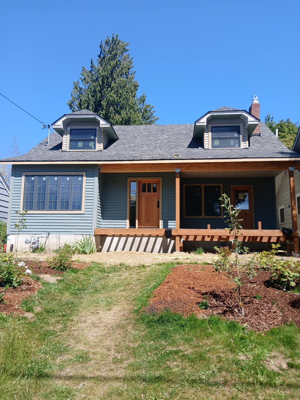 Finished second-story addition on a Sabin bungalow in NE Portland by K&H Construction — twin dormers and new siding, photographed a year after completion