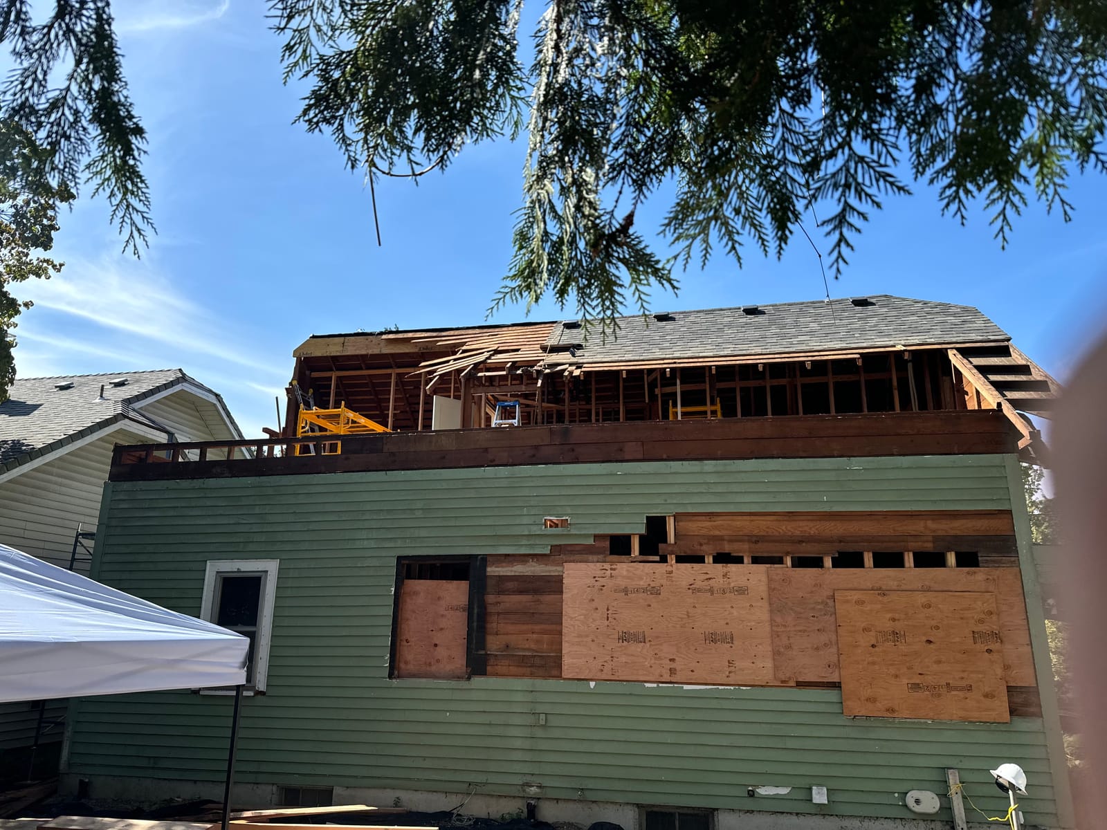 Second story addition under construction on a Sabin bungalow in NE Portland — roof opened and new sheathing going on — K&H Construction
